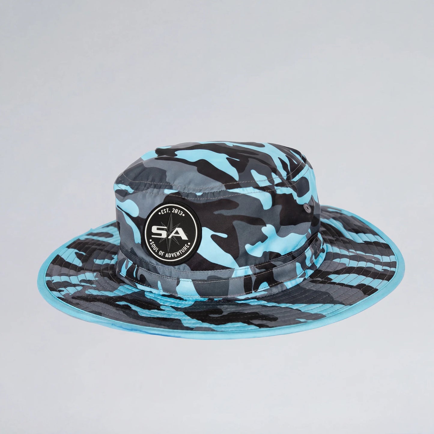 Blue and black camouflage bucket hat with a logo on a light gray background