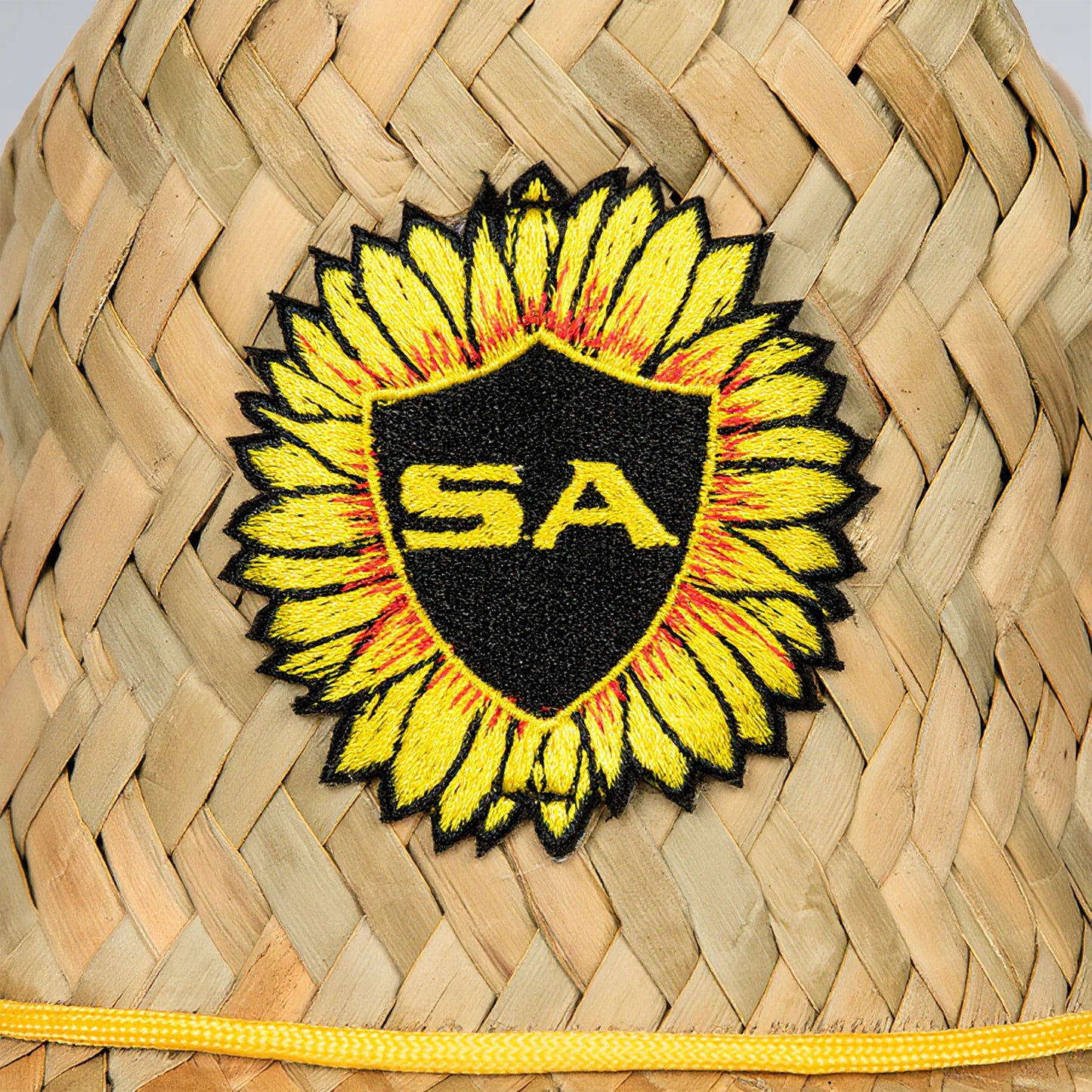 Sunflower-shaped patch with 'SA' logo on a woven surface