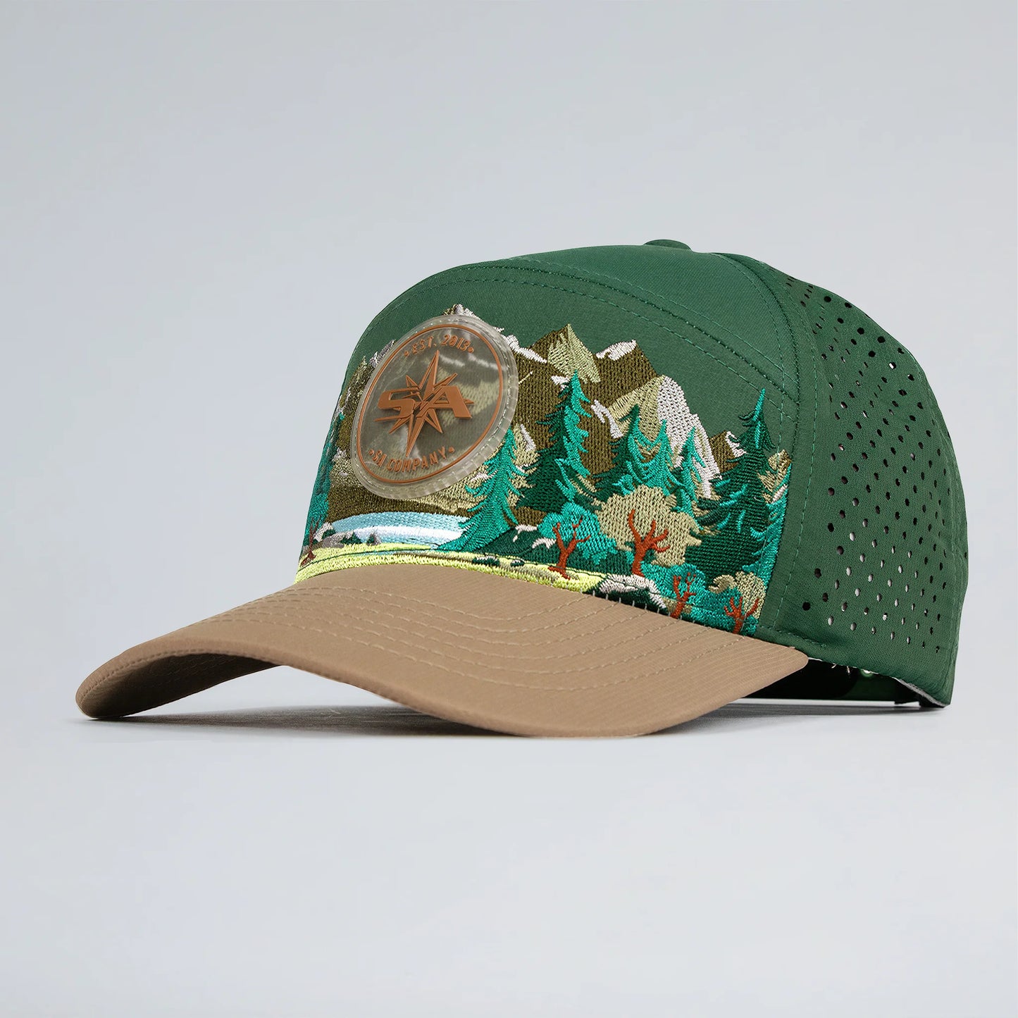 Green and brown cap with embroidered design on a light gray background