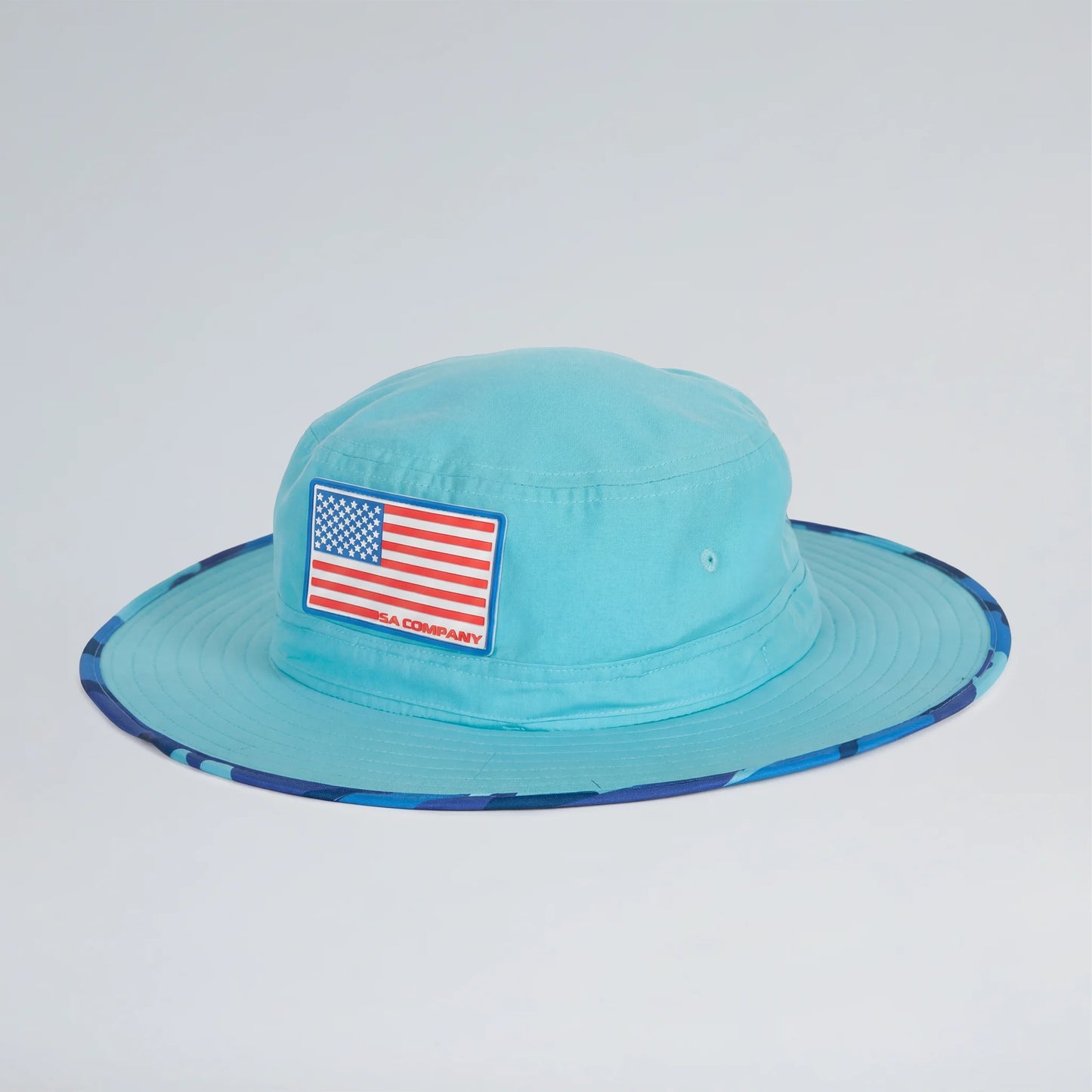 Turquoise bucket hat with American flag patch on a light gray background