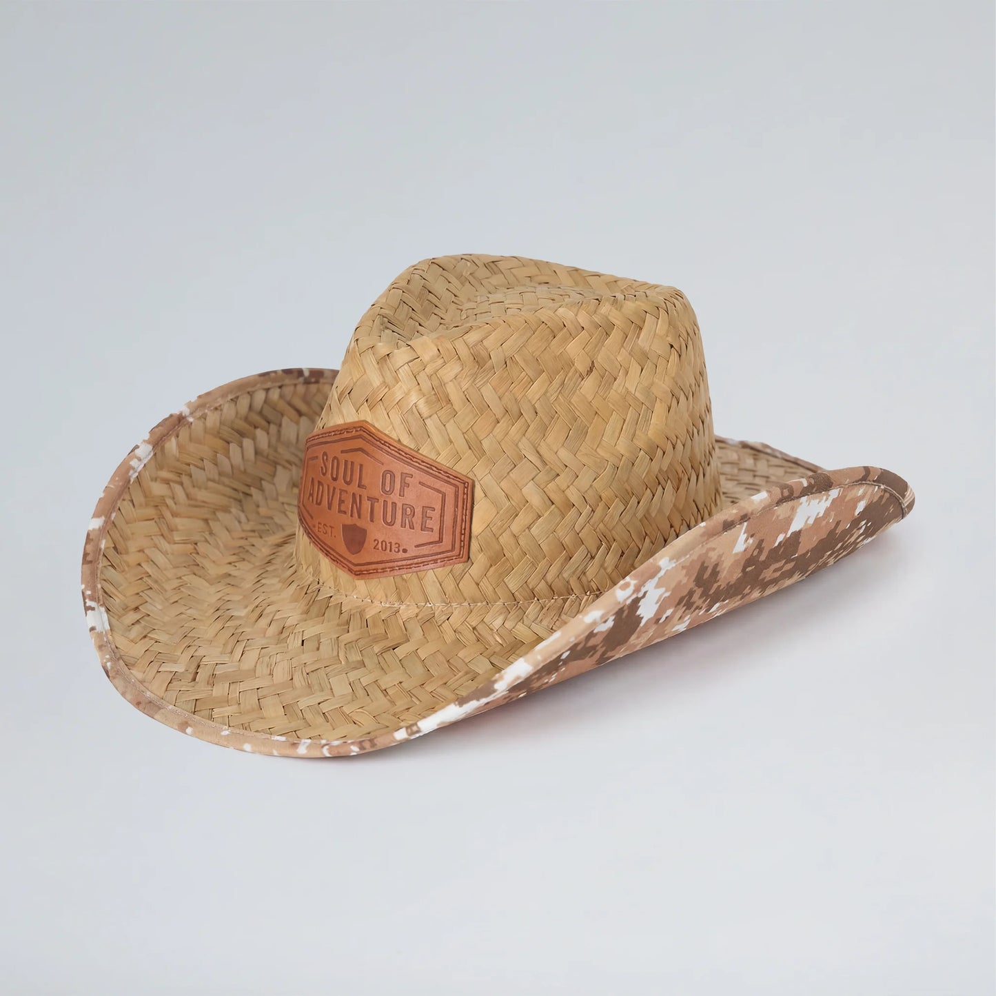 Straw cowboy hat with 'Soul of Adventure' patch on a light gray background