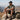 Man sitting on a rock with a mountainous landscape in the background wearing a black performance snapback