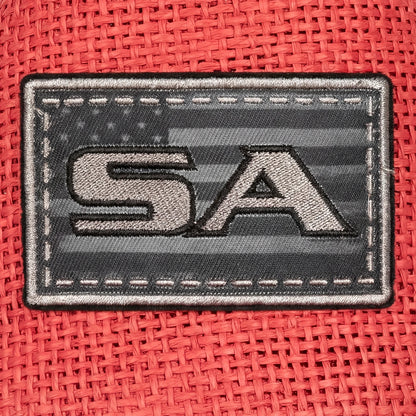 Rectangular patch with 'SA' logo on a red woven background