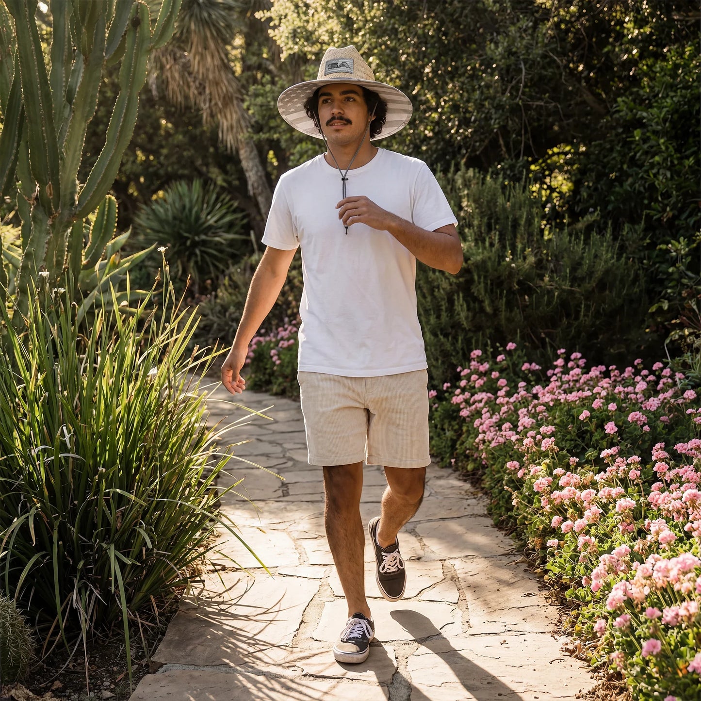 Man walking on a stone path in a garden with plants and flowers