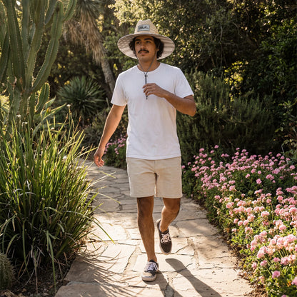 Man walking on a stone path in a garden with plants and flowers