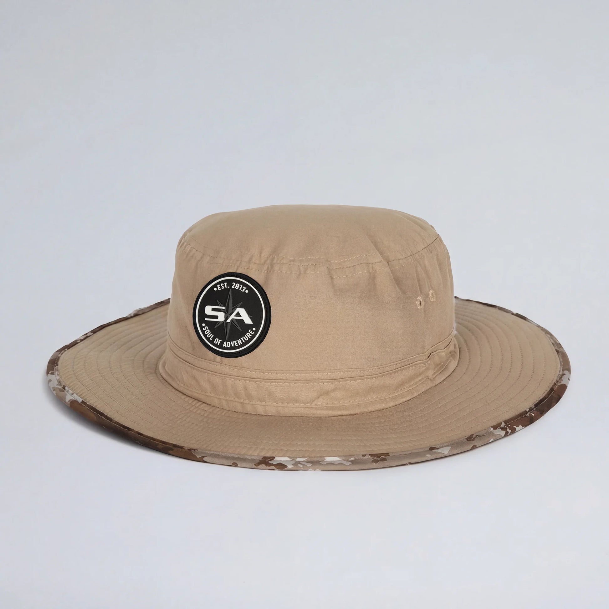 Beige bucket hat with camouflage brim and logo on a light gray background