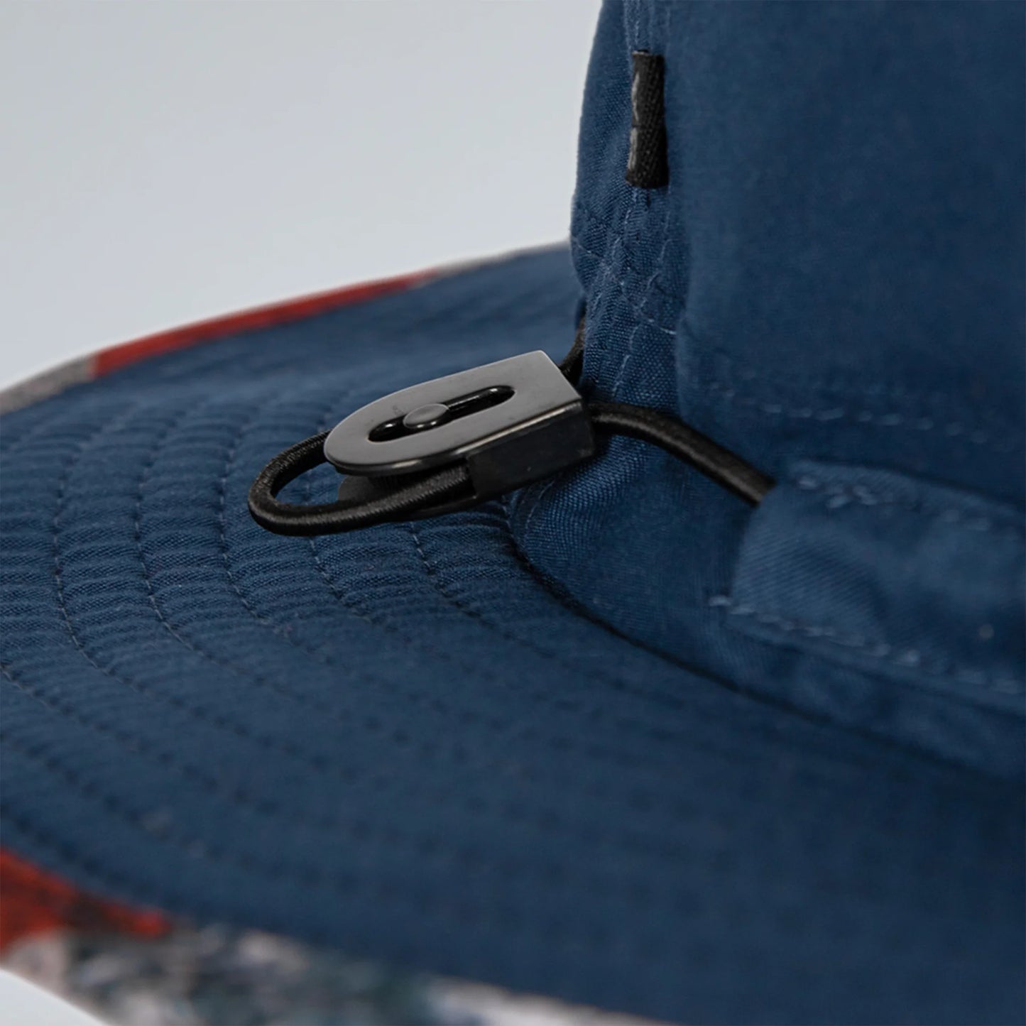 Close-up of a blue cap with a black chin strap on a blurred background