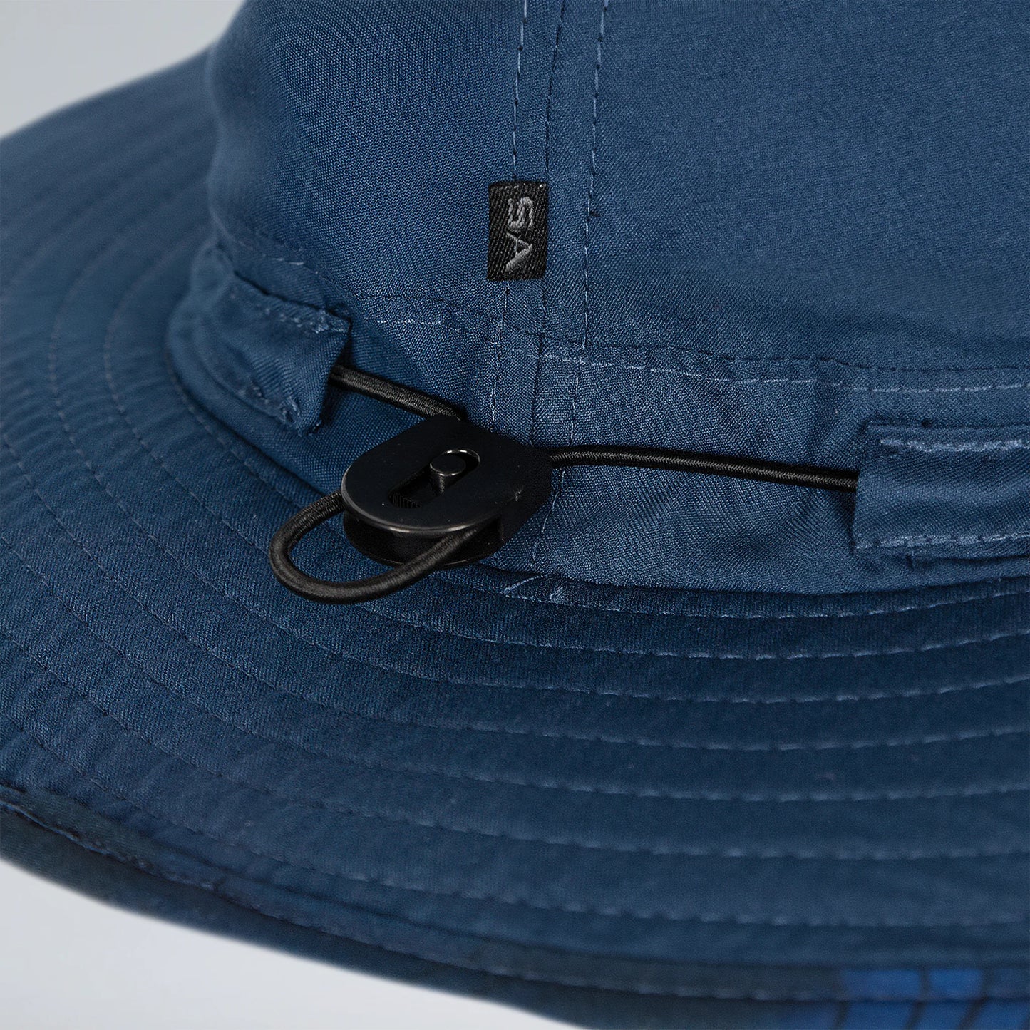Close-up of a blue bucket hat with a black chin strap on a light gray background