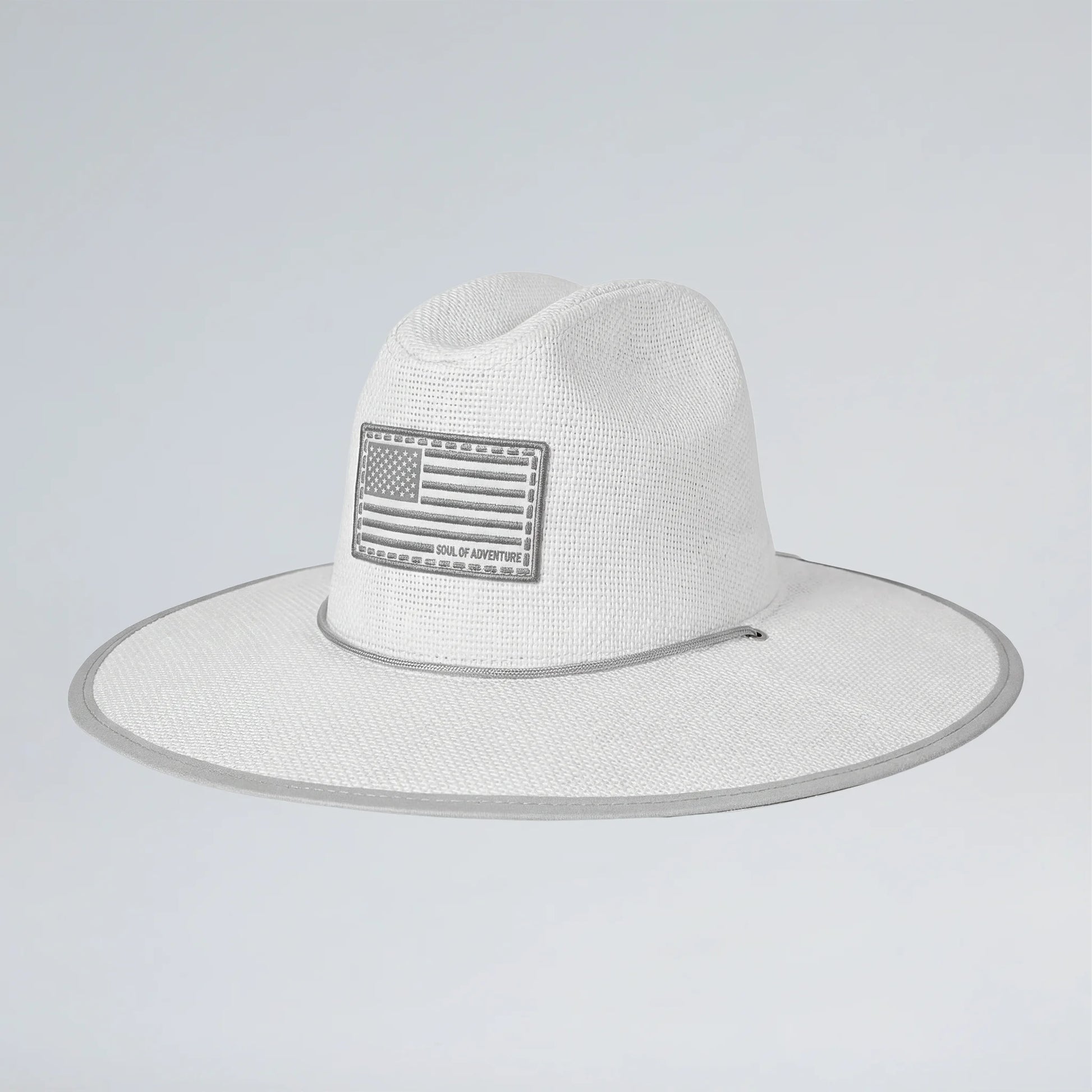 White straw hat with American flag patch on a light gray background