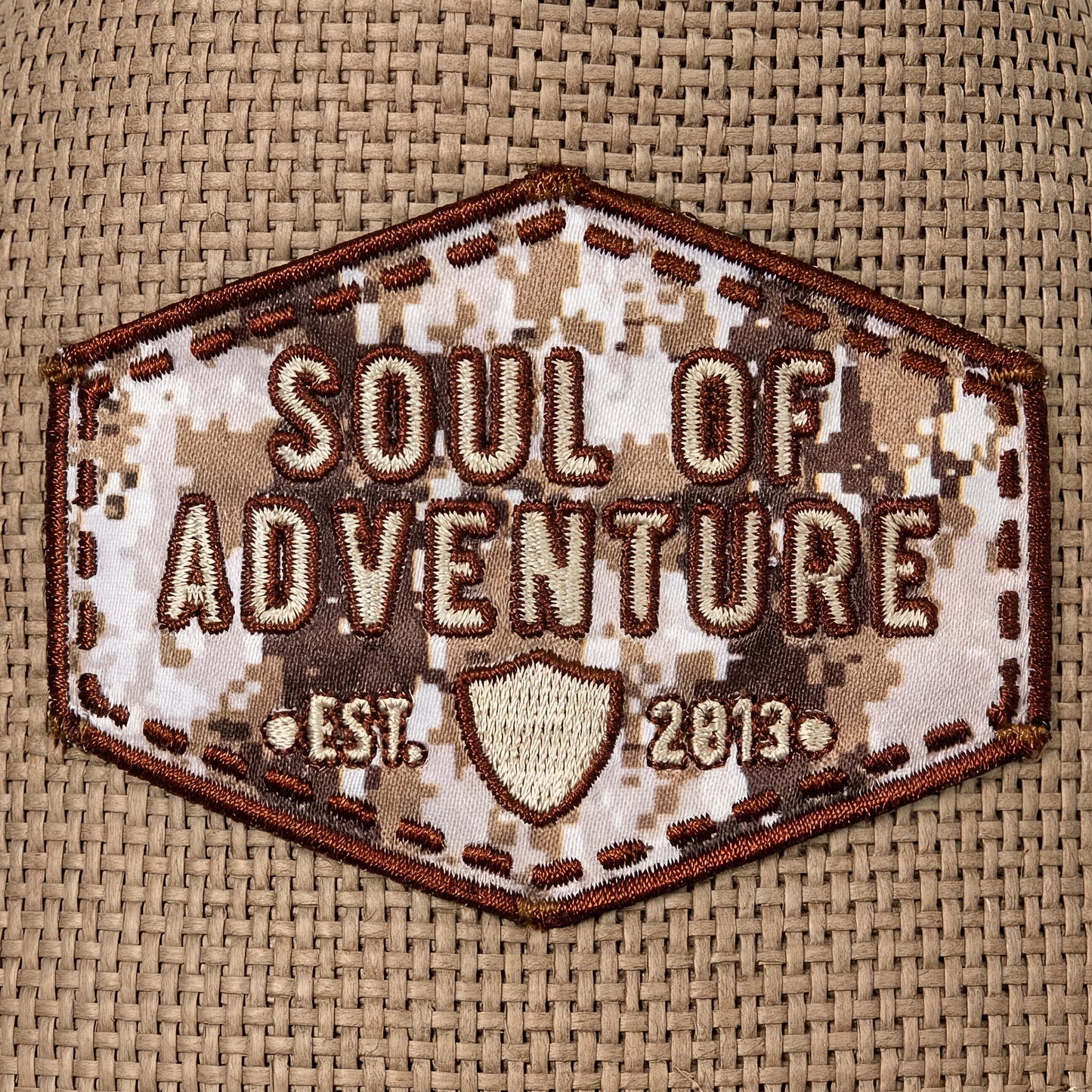 Hexagonal patch with 'Soul of Adventure' text on a camouflage background