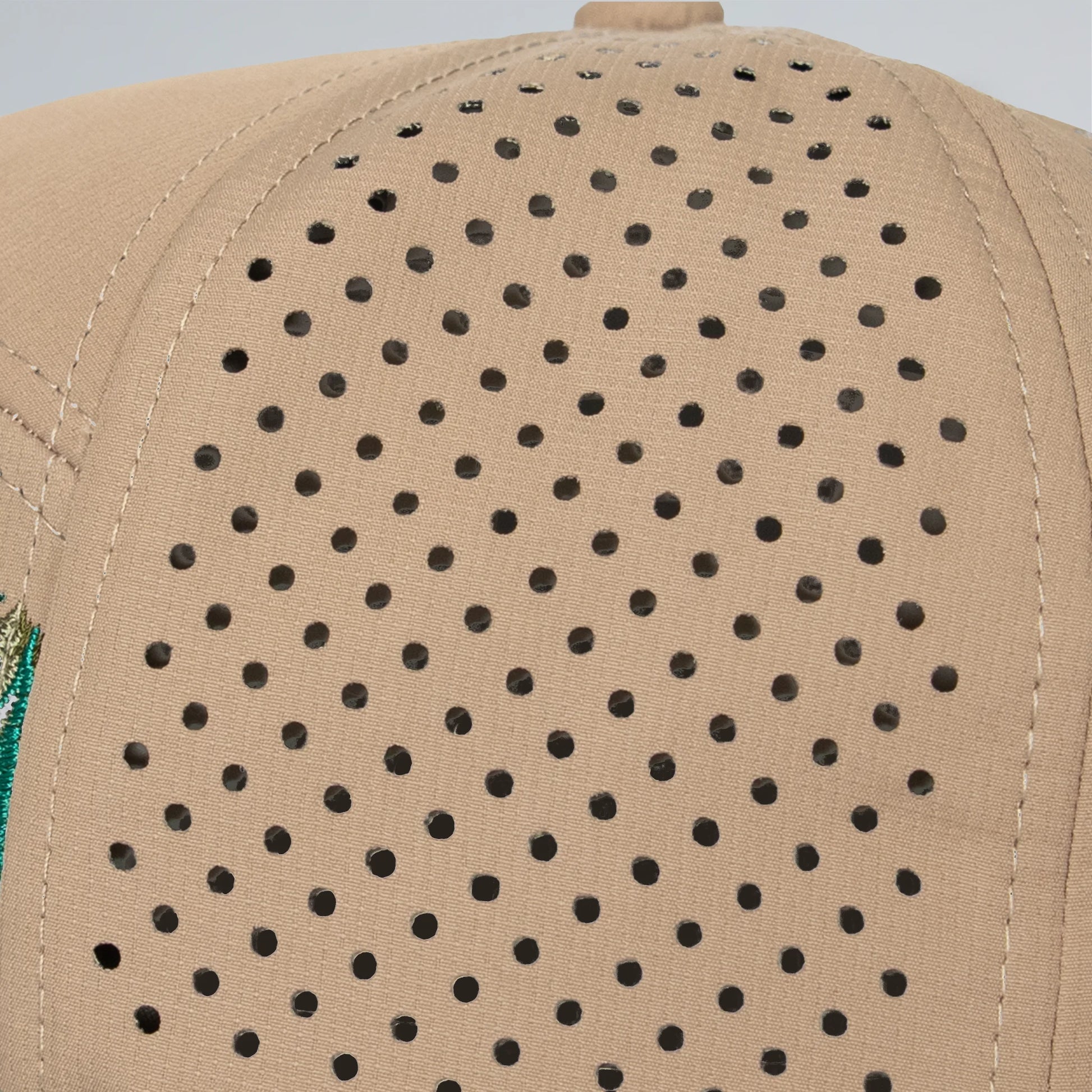 Beige cap with black perforated pattern on a light gray background