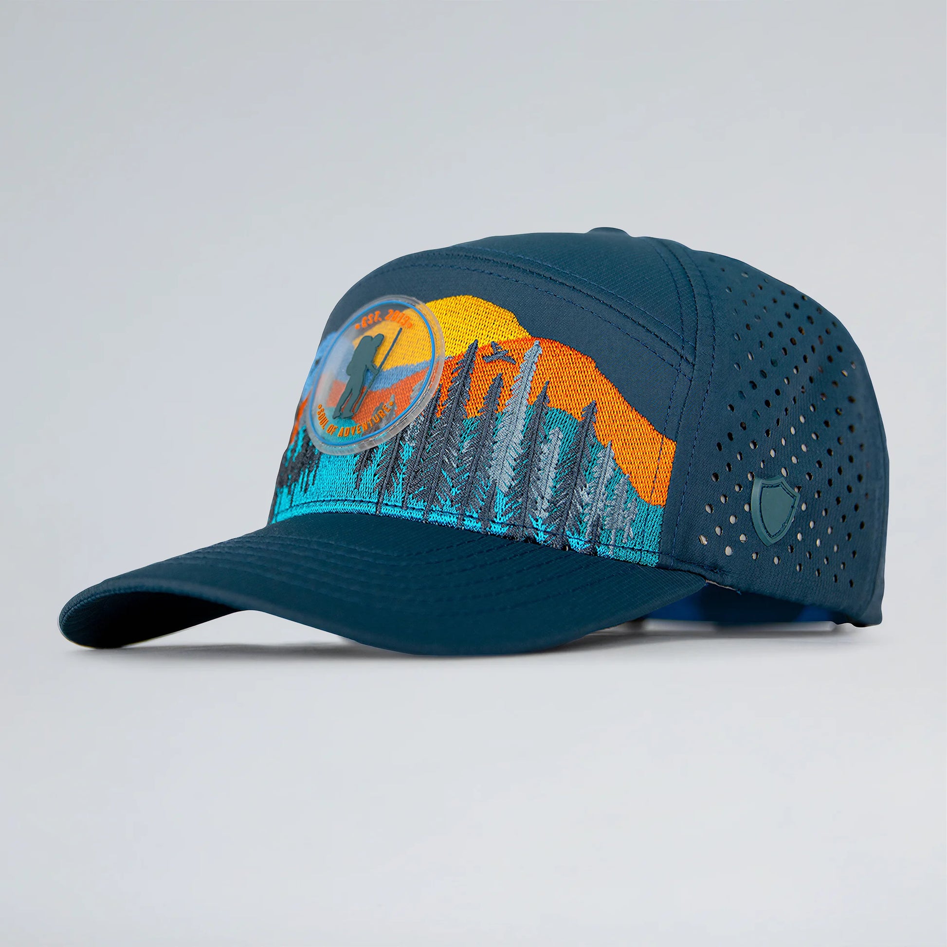Blue cap with mountain and sun design on a light gray background