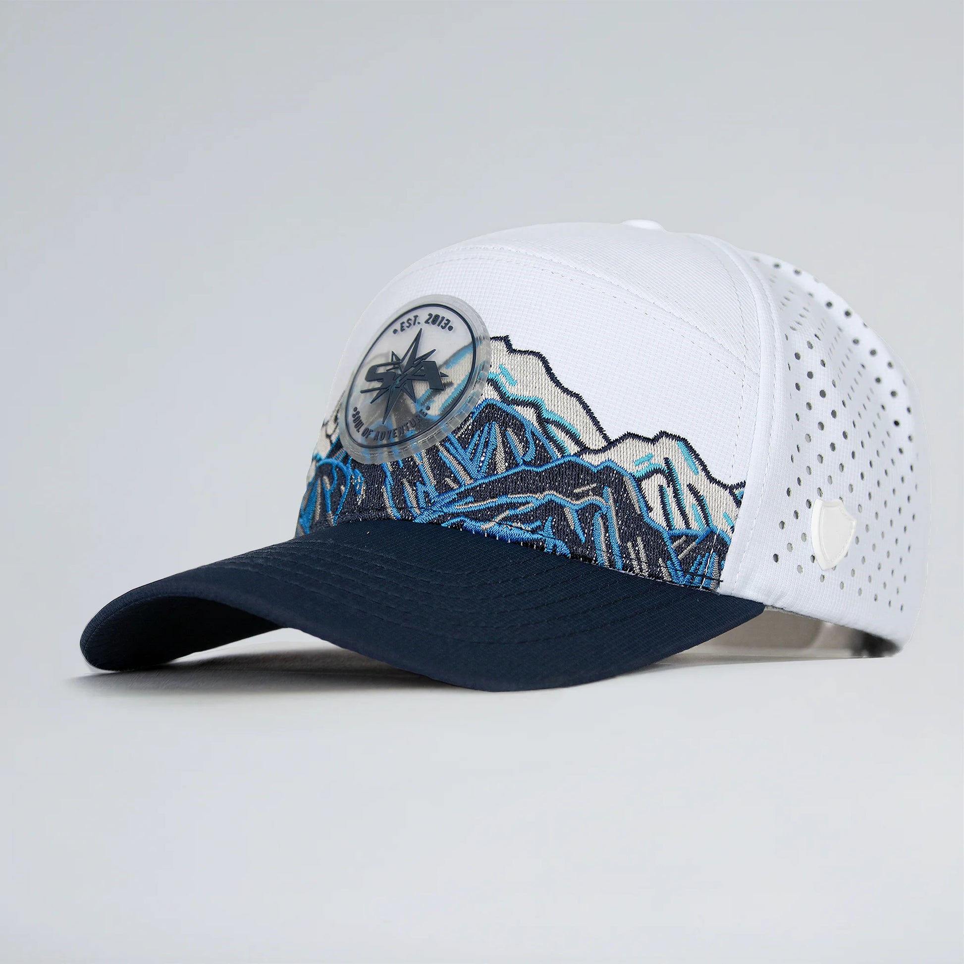 White and navy cap with mountain design on a light gray background