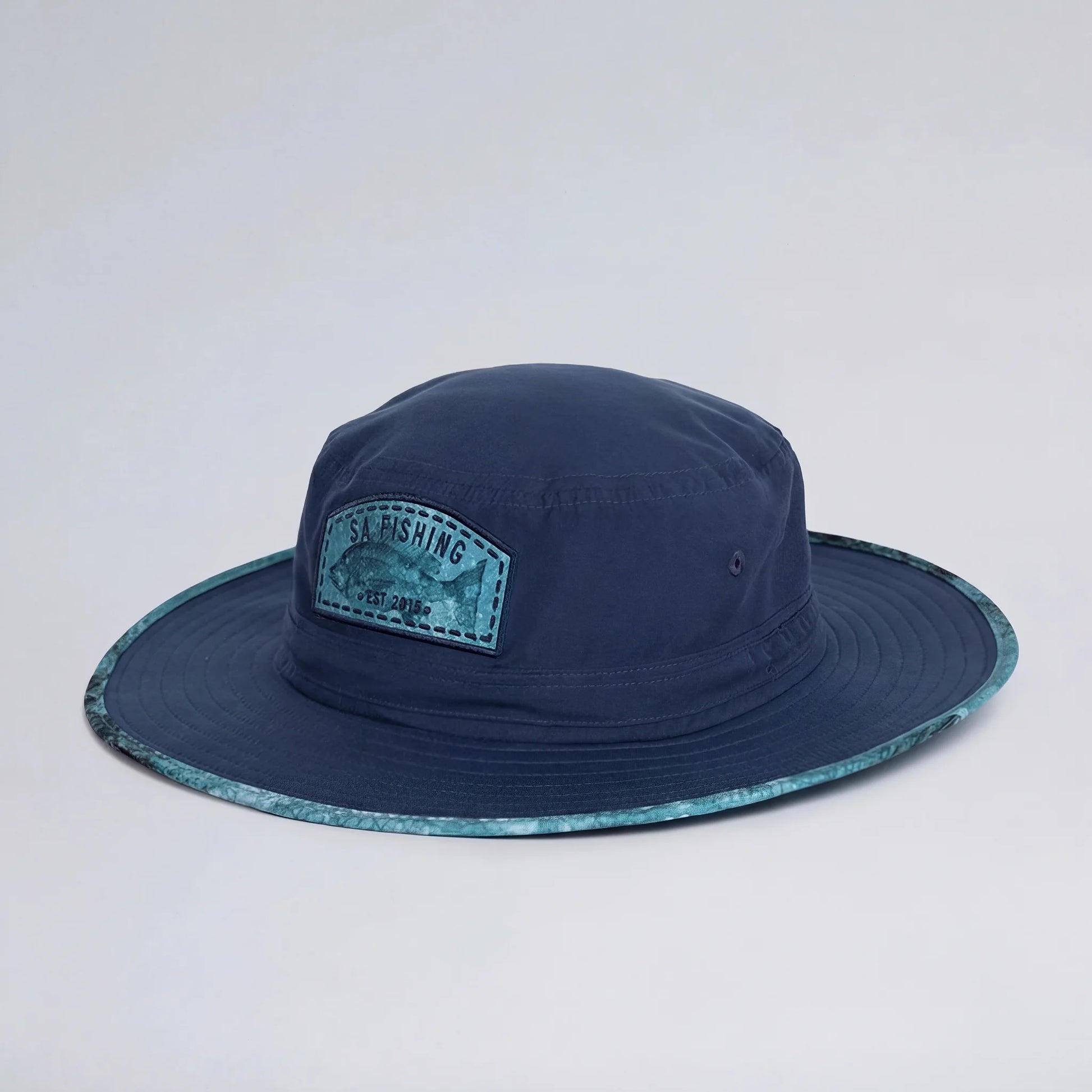 Navy blue fishing hat with a patch on a light gray background