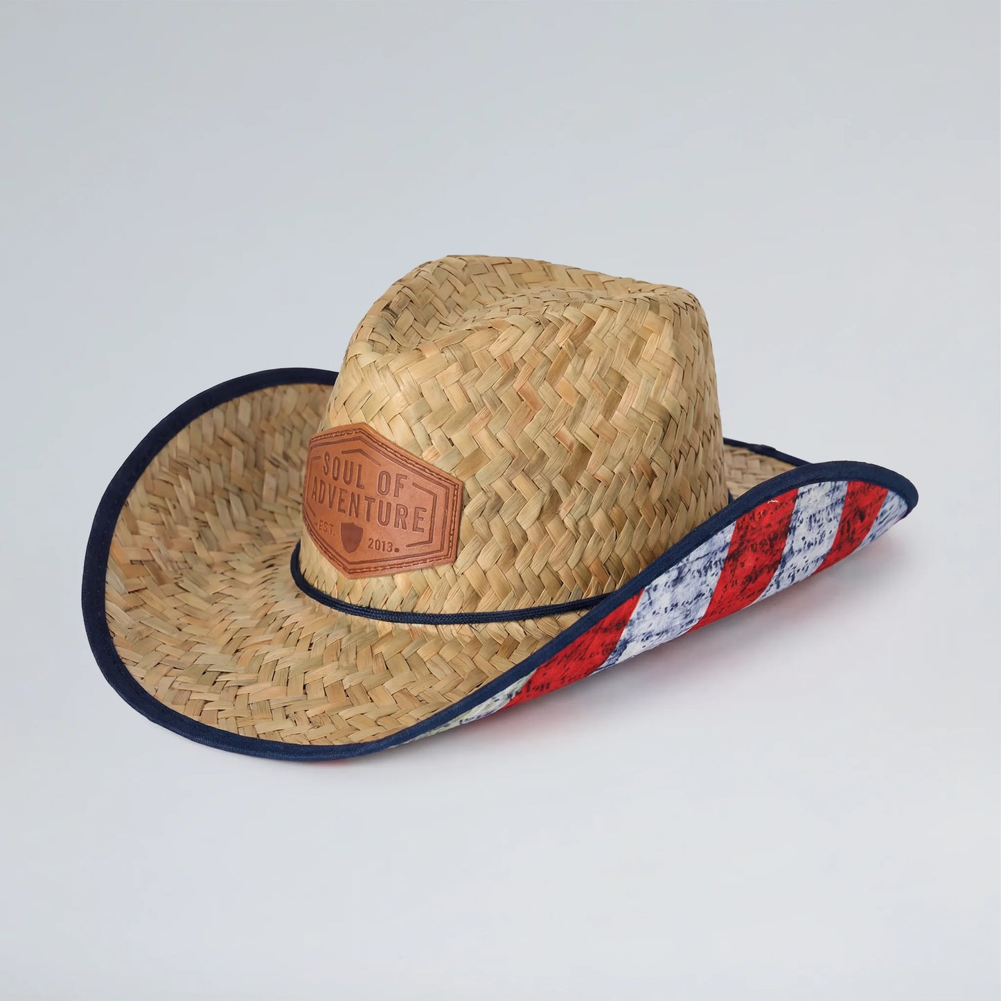 Straw cowboy hat with a colorful band and leather patch on a light gray background