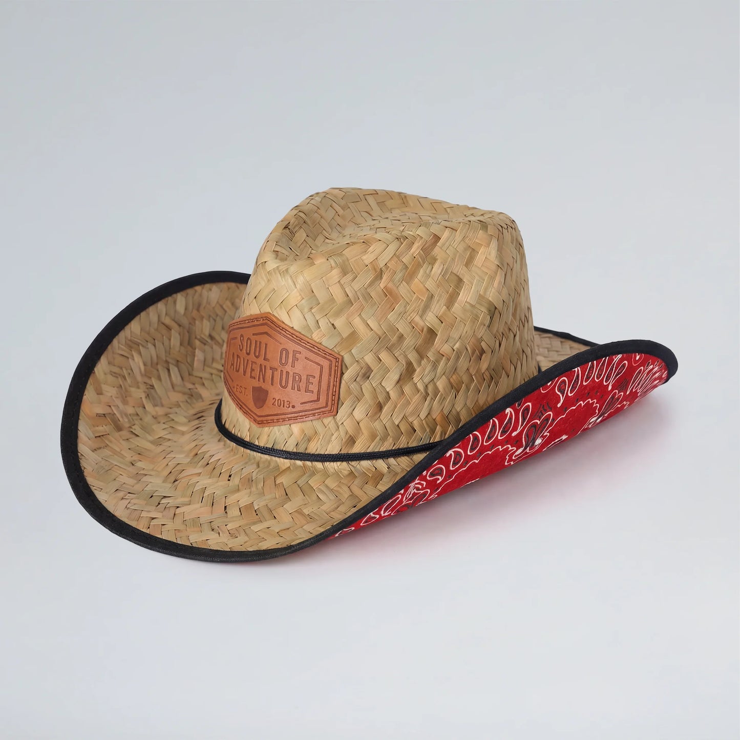 Straw cowboy hat with red bandana and leather patch on a white background