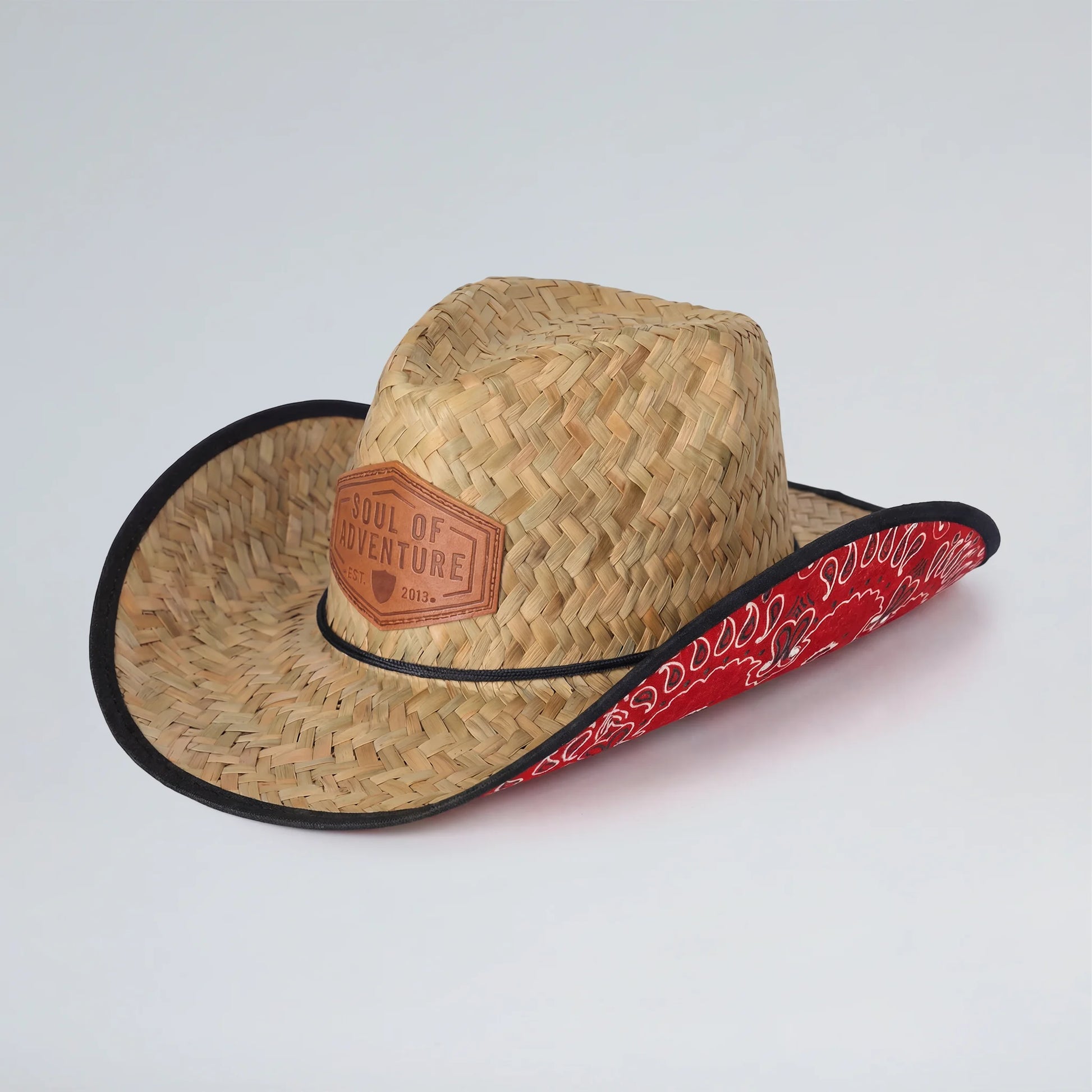 Straw cowboy hat with red bandana and leather patch on a white background
